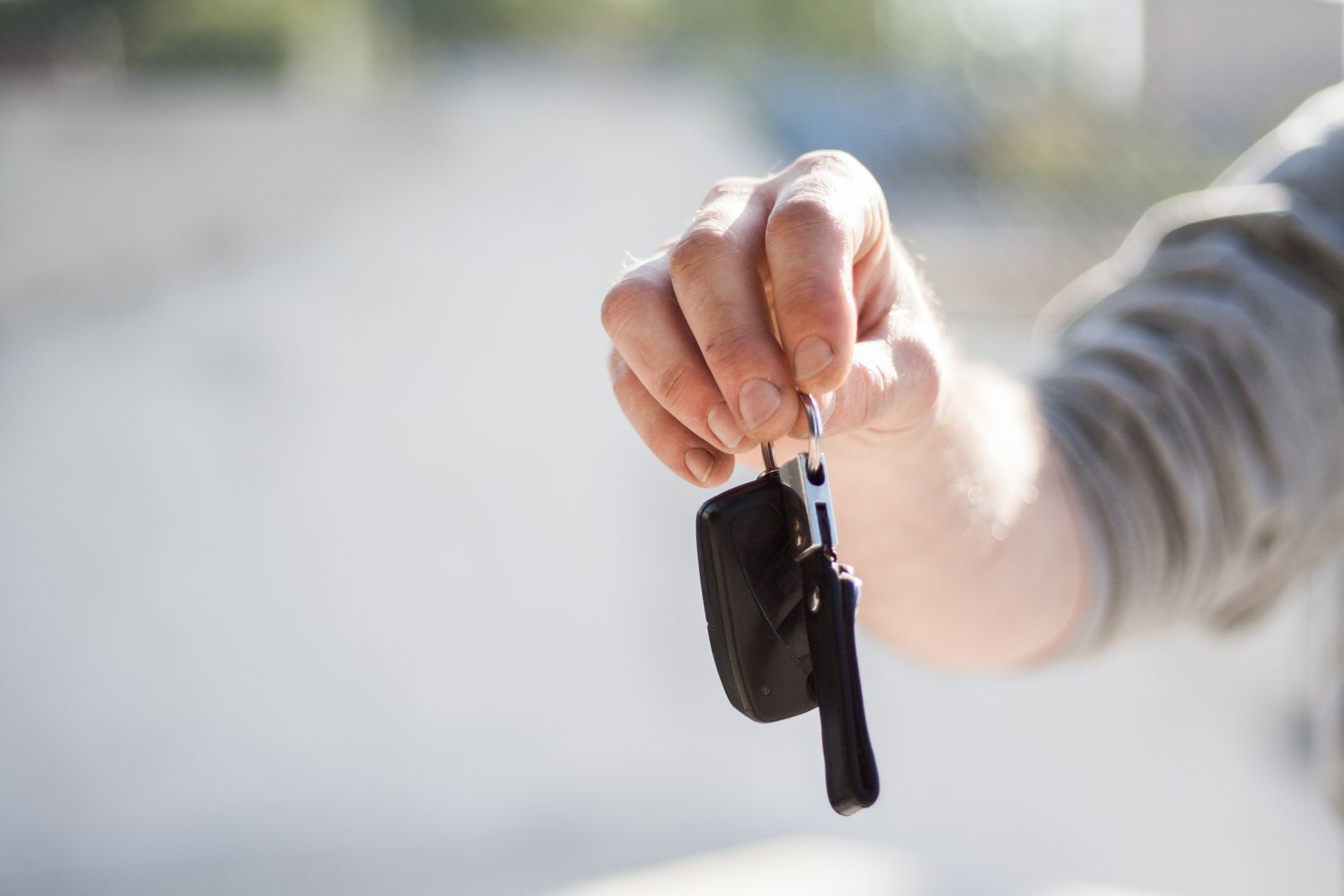 Hand holding out a set of car keys, ready to hand over to a used car buyer